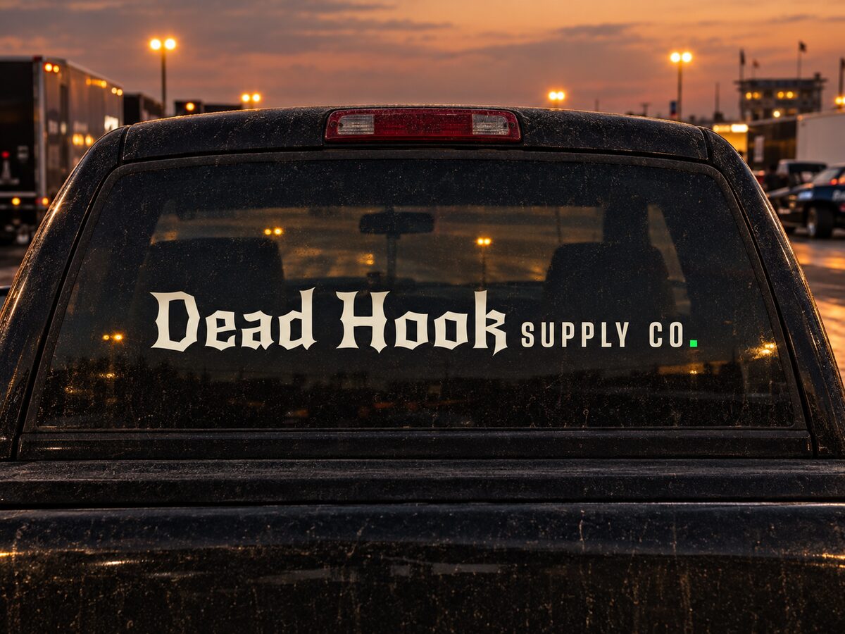 Dead Hook Supply Co. die-cut decal on the rear window of a dusty pickup in a dusk pit area